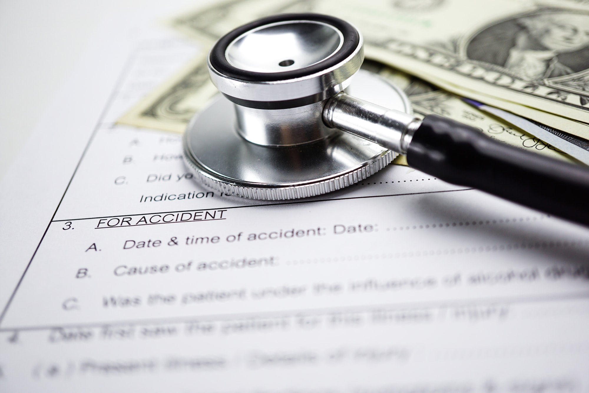 Health insurance accident claim form with stethoscope and US dollar banknotes, Medical concept.
